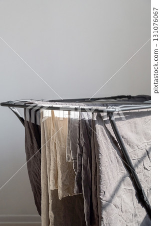Freshly washed laundry hanging on clothes drying rack in sunny room. 131076067