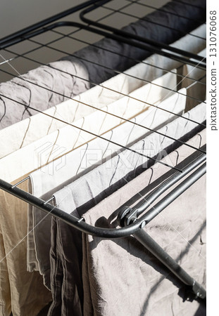 Washed clothes drying on rack near window. Laundry day concept 131076068