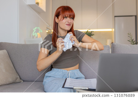 Young woman crumples wrong invoice tosses near laptop plans to print new corrected bill clean copy Young woman crumples wrong invoice tosses near laptop plans to print new corrected bill clean copy 131076889