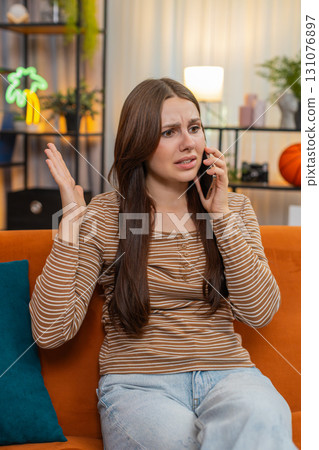 Young woman argues on smartphone frowns sharp hand moves raises voice and speaks fast in tense call Young woman argues on smartphone frowns sharp hand moves raises voice and speaks fast in tense call 131076897