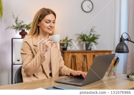 Businesswoman enjoys coffee while working on laptop takes sip smiles refuels energy keeps going 131076966