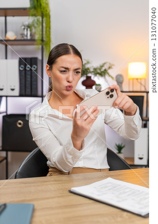 Young businesswoman plays game on smartphone during break beats level smiles and returns to reports 131077040