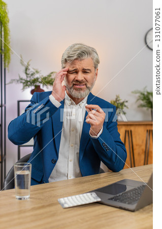 Middle-aged businessman massages temples swallows headache pill drinks water again to return to work Middle-aged businessman massages temples swallows headache pill drinks water again to return to work 131077061