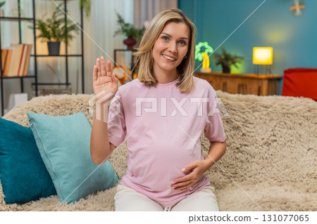Pregnant woman waving greeting smiling hand raised friendly hello connection welcoming gesture open Pregnant woman waving greeting smiling hand raised friendly hello connection welcoming gesture open 131077065