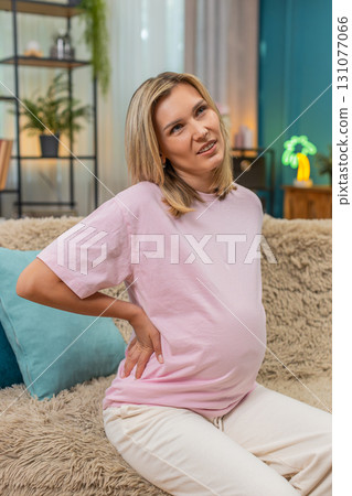 Pregnant woman holding sore lower back pain showing strong discomfort spine strain during pregnancy Pregnant woman holding sore lower back pain showing strong discomfort spine strain during pregnancy 131077066