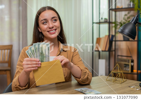 Woman counting dollars cash money placing bills into envelope pleased with careful budget planning Woman counting dollars cash money placing bills into envelope pleased with careful budget planning 131077090
