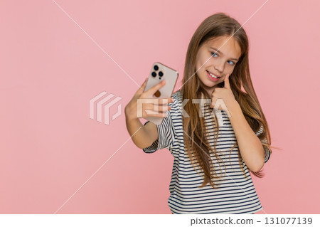 Child girl kid happily taking funny selfies on smartphone laughing joyfully making playful faces 131077139