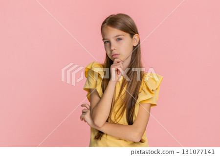 Child girl kid thoughtfully touching chin thinking hard about difficult question solving problem 131077141