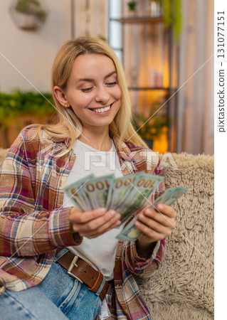 Woman counting cash money at home, smiling proudly while planning budget after lottery win or raise Woman counting cash money at home, smiling proudly while planning budget after lottery win or raise 131077151