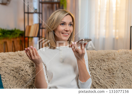 Adult woman talking on smartphone loudspeaker at home, gesturing emotionally while explaining Adult woman talking on smartphone loudspeaker at home, gesturing emotionally while explaining 131077156