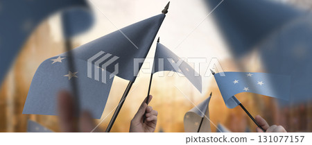 Federated States Micronesia flags in their hands on a blurred urban background Federated States Micronesia flags in their hands on a blurred urban background 131077157