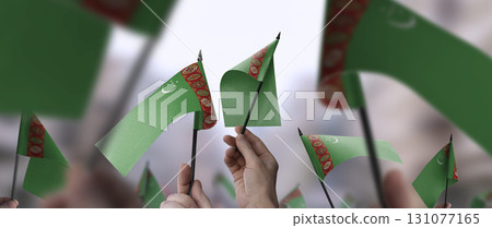 Turkmenistan flags in their hands on a blurred urban background 131077165
