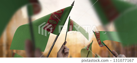 Turkmenistan flags in their hands on a blurred urban background 131077167