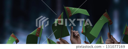 Turkmenistan flags in their hands on a blurred urban background 131077169