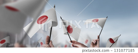 Japan flags in their hands on a blurred urban background 131077185