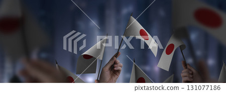 Japan flags in their hands on a blurred urban background Japan flags in their hands on a blurred urban background 131077186