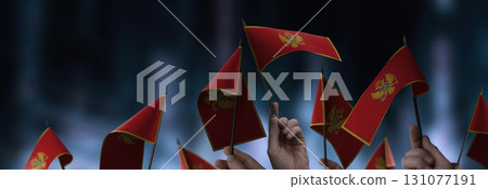 Montenegro flags in their hands on a blurred urban background 131077191