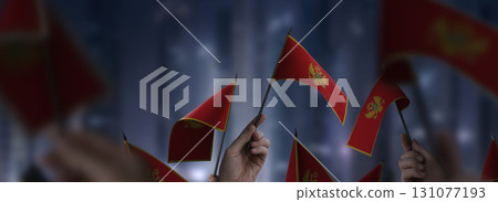 Montenegro flags in their hands on a blurred urban background Montenegro flags in their hands on a blurred urban background 131077193