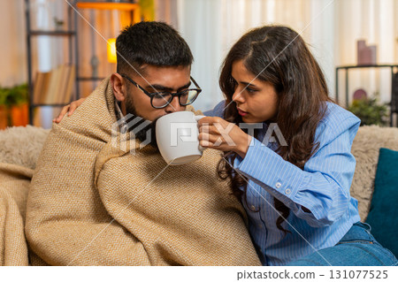 Indian family couple man woman caring for sick ill partner at home, comforting with tea and hugs 131077525