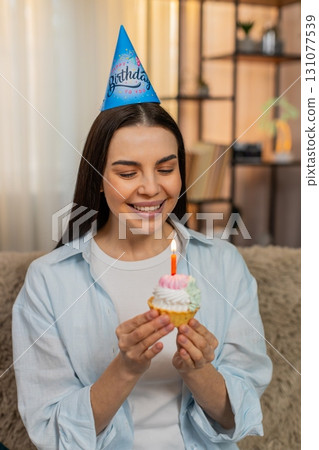 Young woman happily celebrating birthday holding cake with lit candles smiling joyful cheerful mood 131077539
