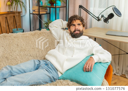 Tired Indian handsome young man guy enjoy relaxing lying on sofa in living room at home apartment 131077576