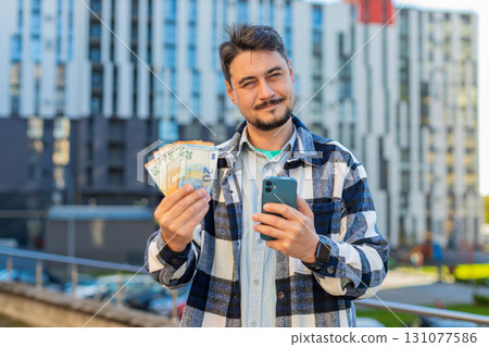 Happy rich mature business man using smartphone and counting money euro on downtown city street 131077586