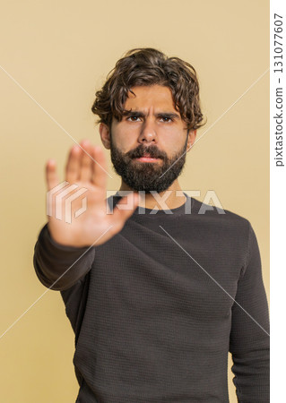 Hindu man says No hold palm in stop gesture, warning of finish prohibited access on beige background 131077607