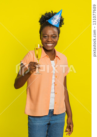 Black young woman raising champagne glass, party hat, birthday celebration, toast for special event Black young woman raising champagne glass, party hat, birthday celebration, toast for special event 131077689