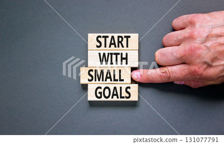 Start with small goals symbol. Concept words phrase Start with small goals on beautiful wooden blocks. Beautiful grey background. Businessman's hand. Business Start with small goals concept Copy space 131077791