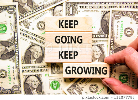 Keep going and growing symbol. Concept words phrase Keep going keep growing on beautiful wooden blocks. Dollar bills. Beautiful dollar bills background. Business Keep going growing concept. Copy space Keep going and growing symbol. Concept words phrase Keep going keep growing on beautiful wooden blocks. Dollar bills. Beautiful dollar bills background. Business Keep going growing concept. Copy space 131077795