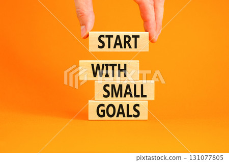 Start with small goals symbol. Concept words phrase Start with small goals on beautiful wooden blocks. Beautiful orange background Businessman's hand Business Start with small goals concept Copy space 131077805