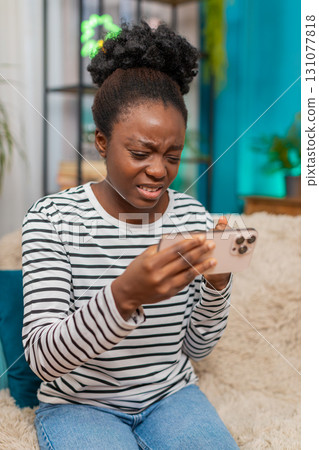 Irritated African woman frustrated losing fail playing video online game on smartphone at home Irritated African woman frustrated losing fail playing video online game on smartphone at home 131077818