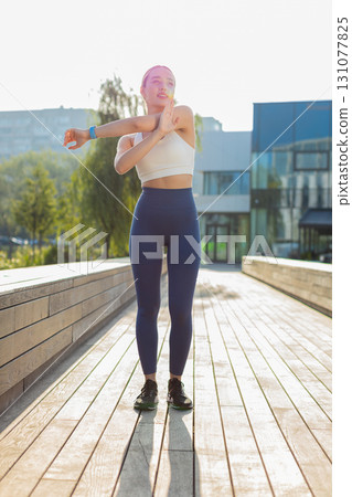 Caucasian sporty young woman runner stretching arms warm up before jogging in city park on sunny day Caucasian sporty young woman runner stretching arms warm up before jogging in city park on sunny day 131077825