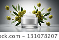 A glass jar contains rich, white facial cream, glowing softly. Fresh olive fruits and green leaves float around, adding a natural touch to the scene, creating an inviting and refreshing atmosphere. 131078207