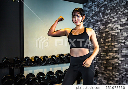女人炫耀她的二頭肌，酷女人在健身房鍛煉，上身，肌肉訓練女孩 131078530
