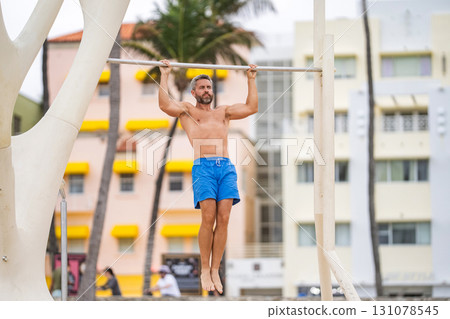 Muscular man sportsman with strong six pack muscle. Sport pullup workout. Sport training. Man sportsman do pulling exercise. Man muscular six pack athlete doing pull up in outdoor gym Muscular man sportsman with strong six pack muscle. Sport pullup workout. Sport training. Man sportsman do pulling exercise. Man muscular six pack athlete doing pull up in outdoor gym 131078545