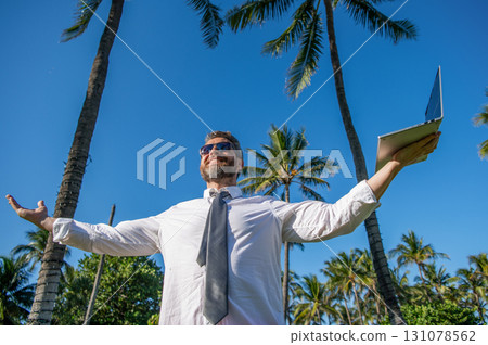 Businessman boss with laptop. Business man using laptop near palm tree. Business trip. Man freelance work online at beach. Businessman on summer vacation. Online freelance work. Flexible schedule 131078562
