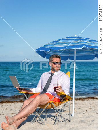 Businessman on summer vacation. Online freelance. Businessman remote worker with laptop. Business man using laptop in beach. Travel and business. Man freelance work online at sea beach 131078563