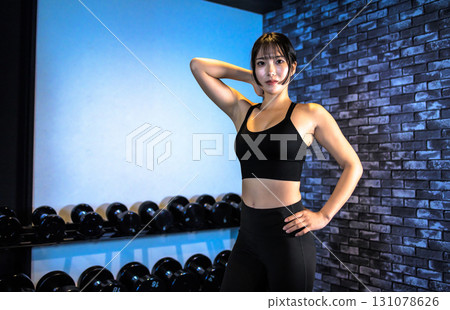 A well-trained young woman posing. A cool woman exercising at the gym. Posing. Muscle training girl. 131078626
