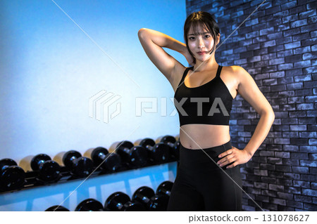 一位訓練有素的年輕女子擺姿勢。一位酷酷的女人在健身房鍛鍊。擺姿勢。肌肉訓練女孩。 131078627