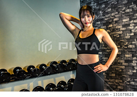 一位訓練有素的年輕女子擺姿勢。一位酷酷的女人在健身房鍛鍊。擺姿勢。肌肉訓練女孩。 一位訓練有素的年輕女子擺姿勢。一位酷酷的女人在健身房鍛鍊。擺姿勢。肌肉訓練女孩。 131078628