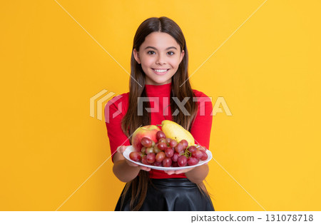 positive girl hold fresh fruit plate on yellow background. selective focus positive girl hold fresh fruit plate on yellow background. selective focus 131078718