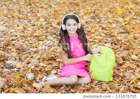 school girl wear headphones while sit near backpack outdoor, back to school school girl wear headphones while sit near backpack outdoor, back to school 131078785