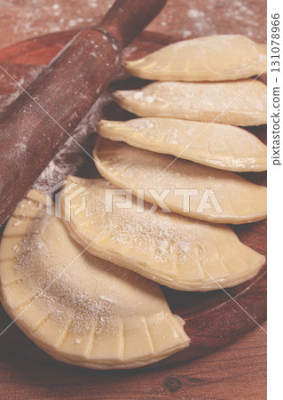 raw chebureks, mini, on a cutting board, wooden table, close-up, no people, 131078966
