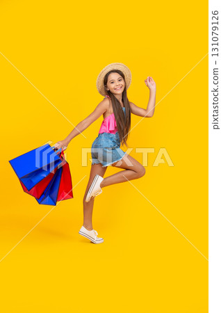 happy teen girl hurry up with shopping bags on yellow background. full length happy teen girl hurry up with shopping bags on yellow background. full length 131079126