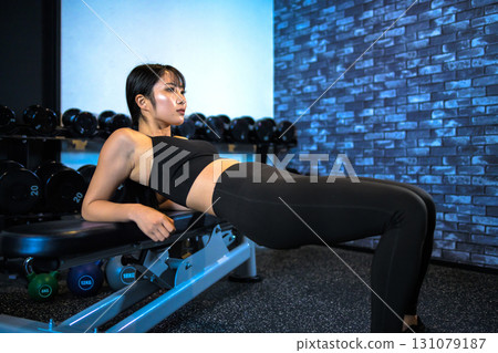 Young woman training her buttocks with hip thrusts. Cool woman exercising at the gym. Hip up. Muscle training girl. Young woman training her buttocks with hip thrusts. Cool woman exercising at the gym. Hip up. Muscle training girl. 131079187