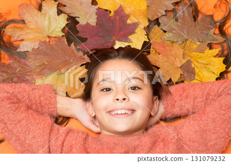 With smile on her lips. Happy smile of beauty model. Small child with cute smile. Little girl in autumn mood. Kid smiling with colorful leaves in long hair. Fall season starts with beautiful smile With smile on her lips. Happy smile of beauty model. Small child with cute smile. Little girl in autumn mood. Kid smiling with colorful leaves in long hair. Fall season starts with beautiful smile 131079232