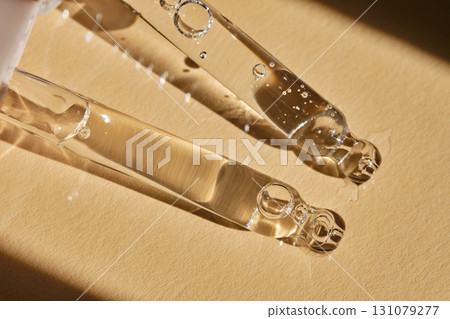 Two pipettes with serum on a beige background. 131079277