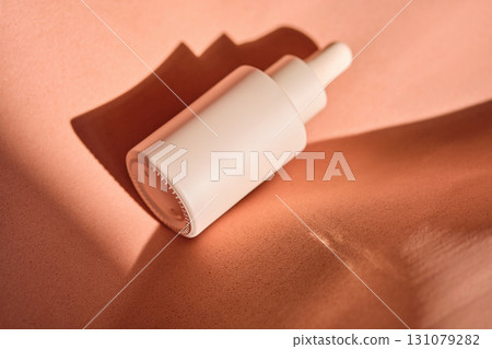 A bottle of serum in beige and peach tones. 131079282