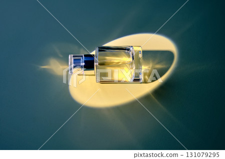 A bottle of perfume in a yellow ray on a blue background. 131079295